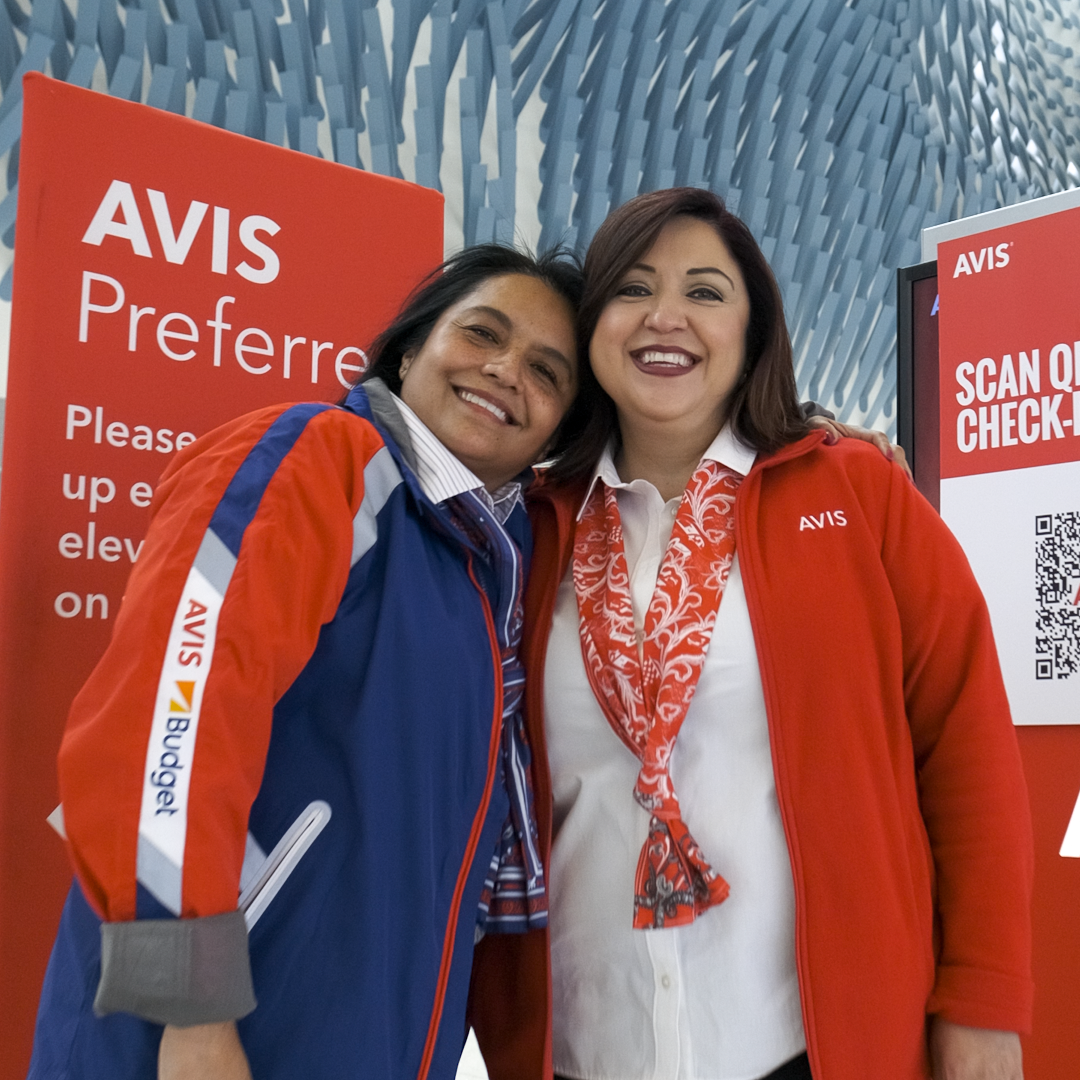 2 ladies standing in front of Avis signs